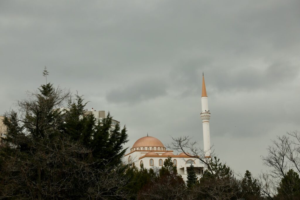 Kubah masjid tembaga dan menara di antara pepohonan rindang